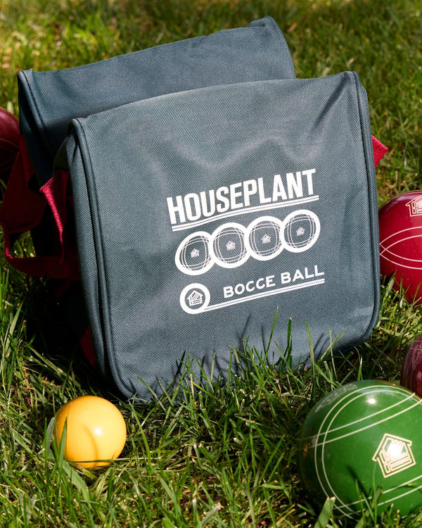 Bocce ball set with green and red balls and a gray bag on grass