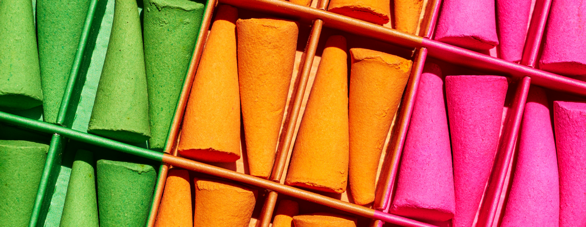 Green, orange and pink incense cones arranged in a divided box