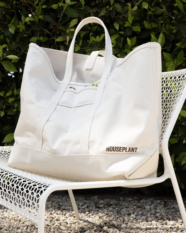 White tote bag with 'HOUSEPLANT' branding on a metal chair outdoors.